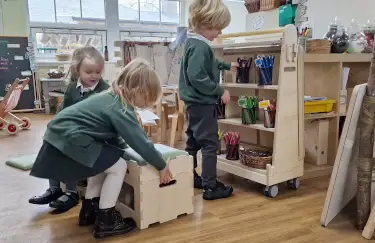 primary school pupils using classroom stools and shelves