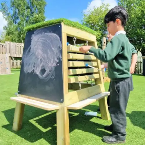 school pupil playing with freestanding music easel outside