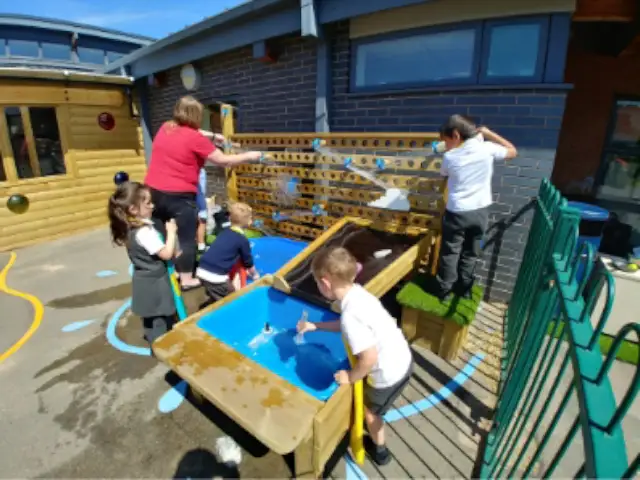 primary school children playing with water table and water wall outside