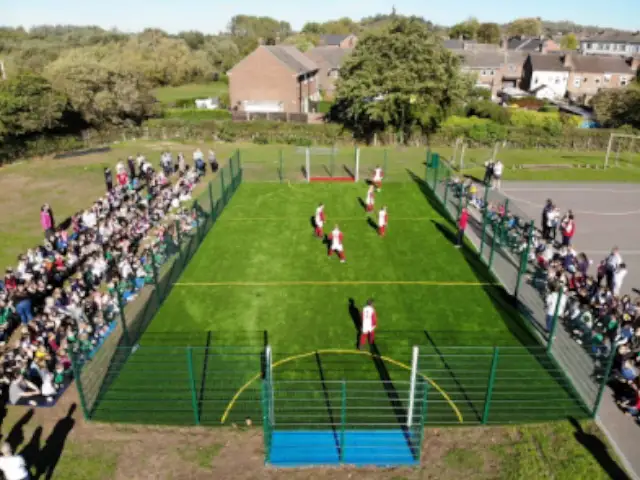 school students playing football in school playground MUGA