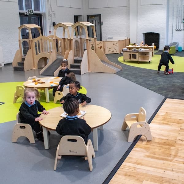 A group of children playing with nursery furniture in a classroom