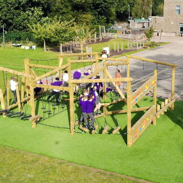 A large climbing frame that has been installed on artificial grass with children climbing all over it.