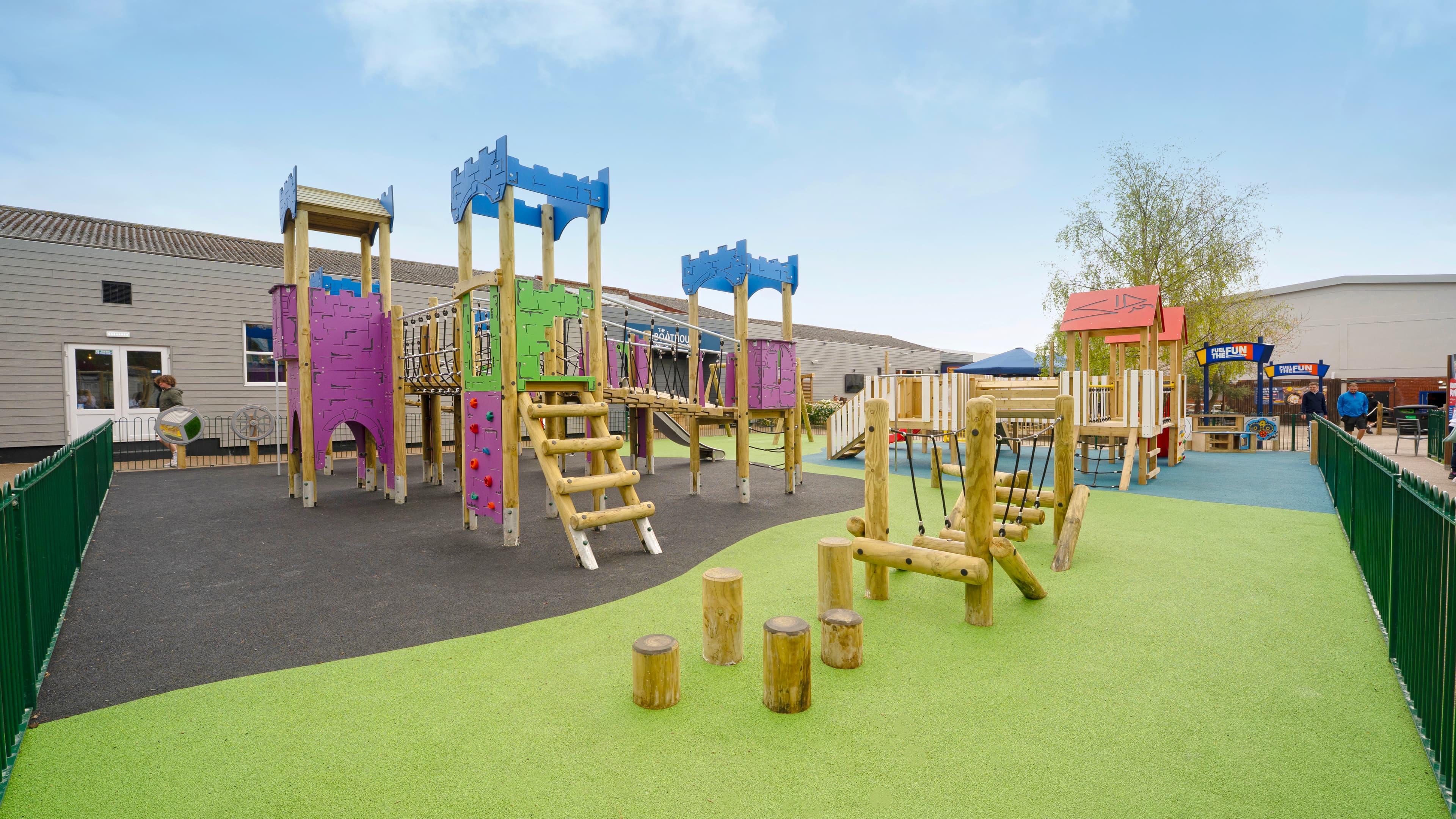 multi-use-games-area with artificial grass and fencing alongside a clmbing frame, play tower, outdoor classroom and tyre trim trail