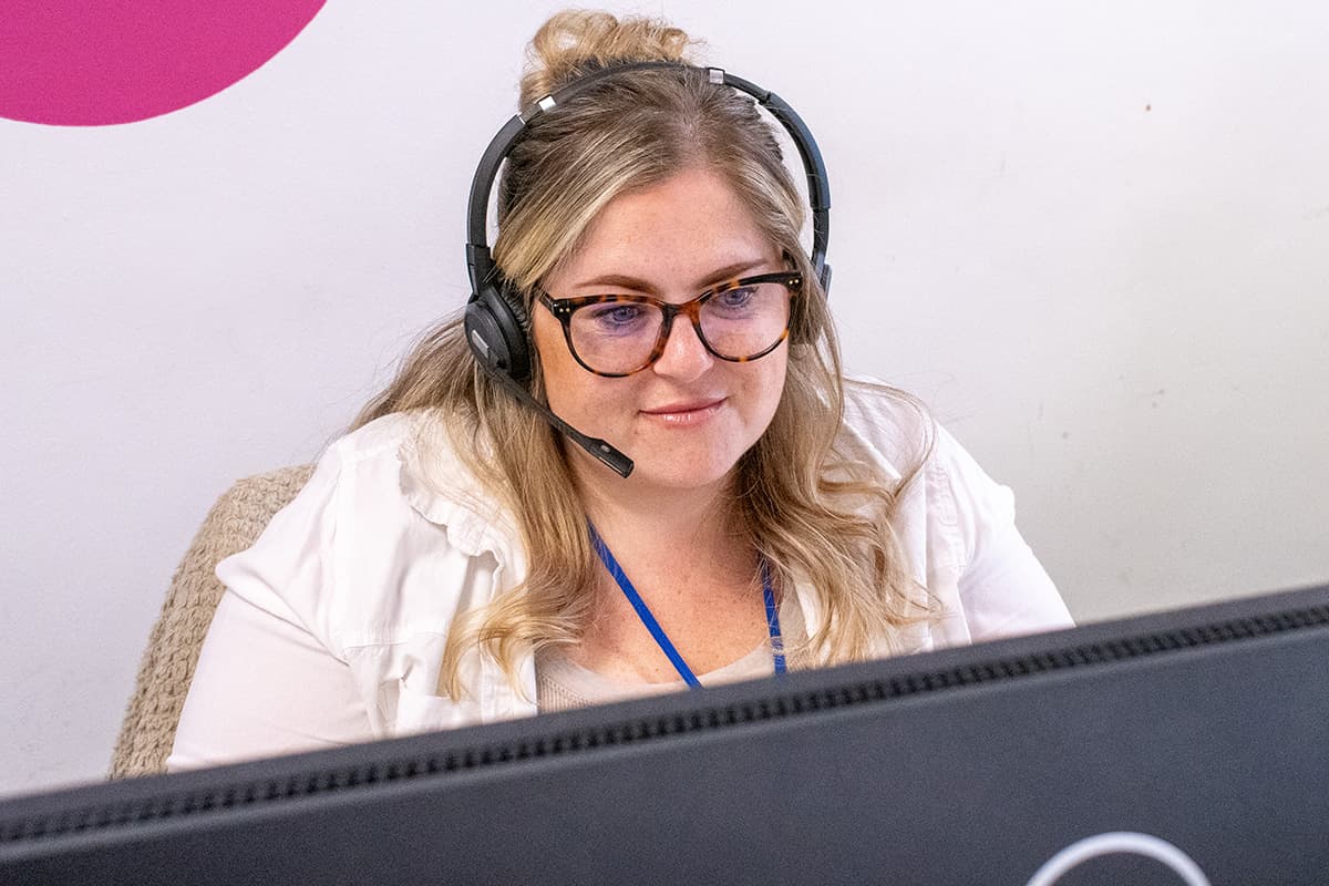a woman with blonde head, wearing a headset, in an office