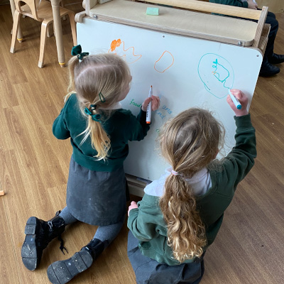 two students drawing on whiteboard of art easel