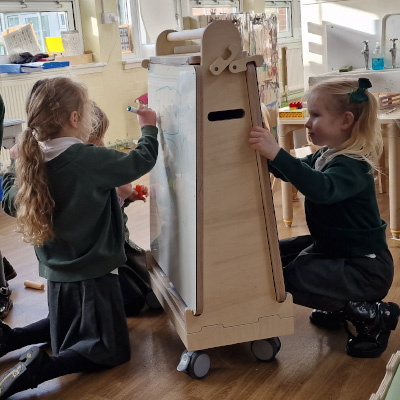 two school children using the art easel from both sides
