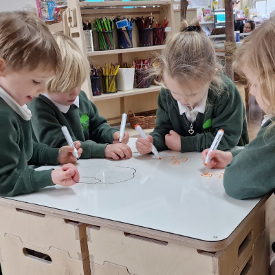 pupils writing on whiteboard table with stack and sit stools