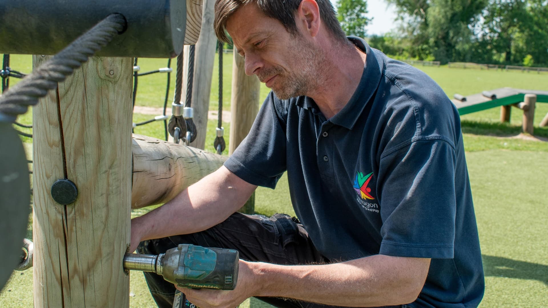 A man is testing the strength of a metallic bar that is attached to a rope climbing frame. The main is putting his body weight on the rope climbing frame
